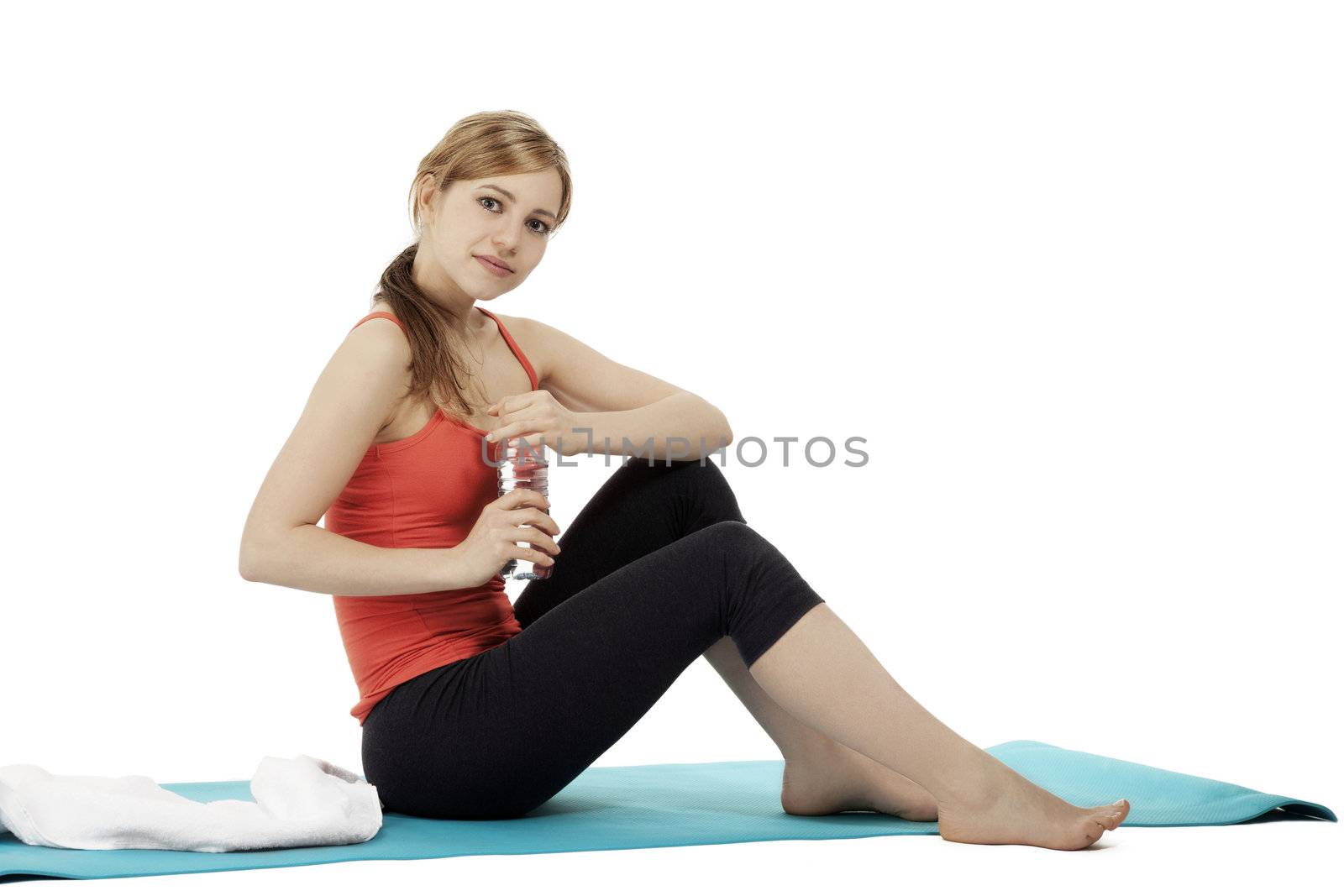 sitting young fitness woman about to open a bottle of water on white background
