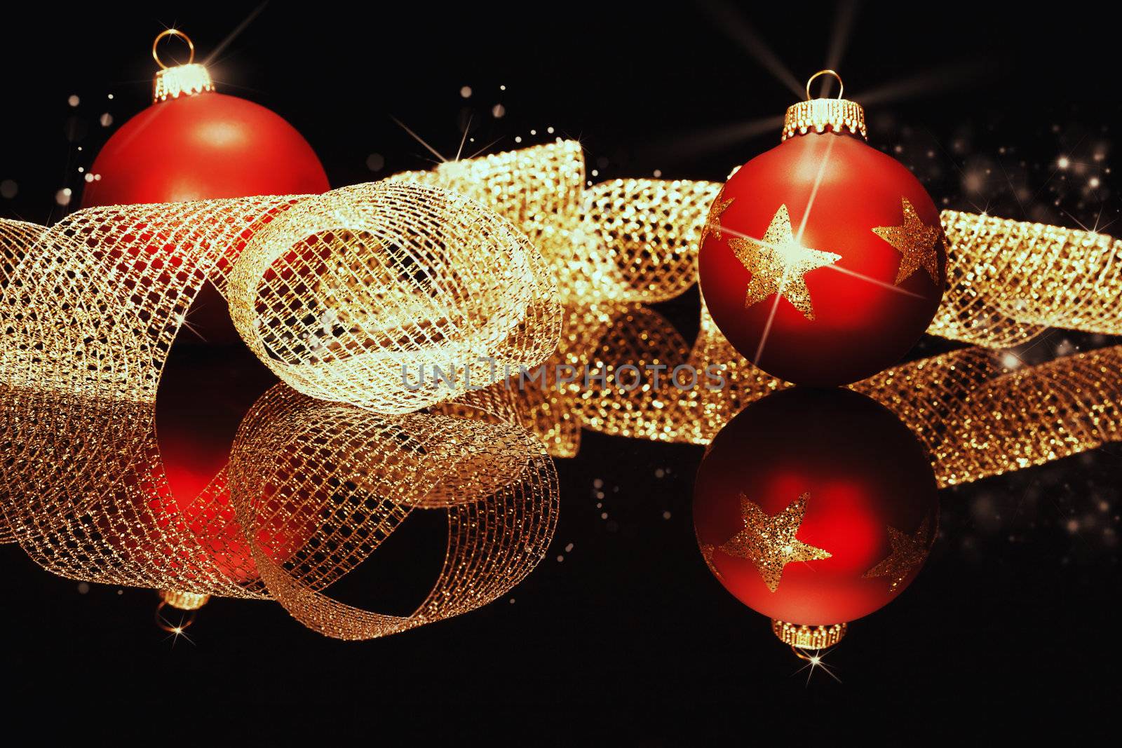 red christmas balls with glitter stars with golden metal ribbon on a black mirror 