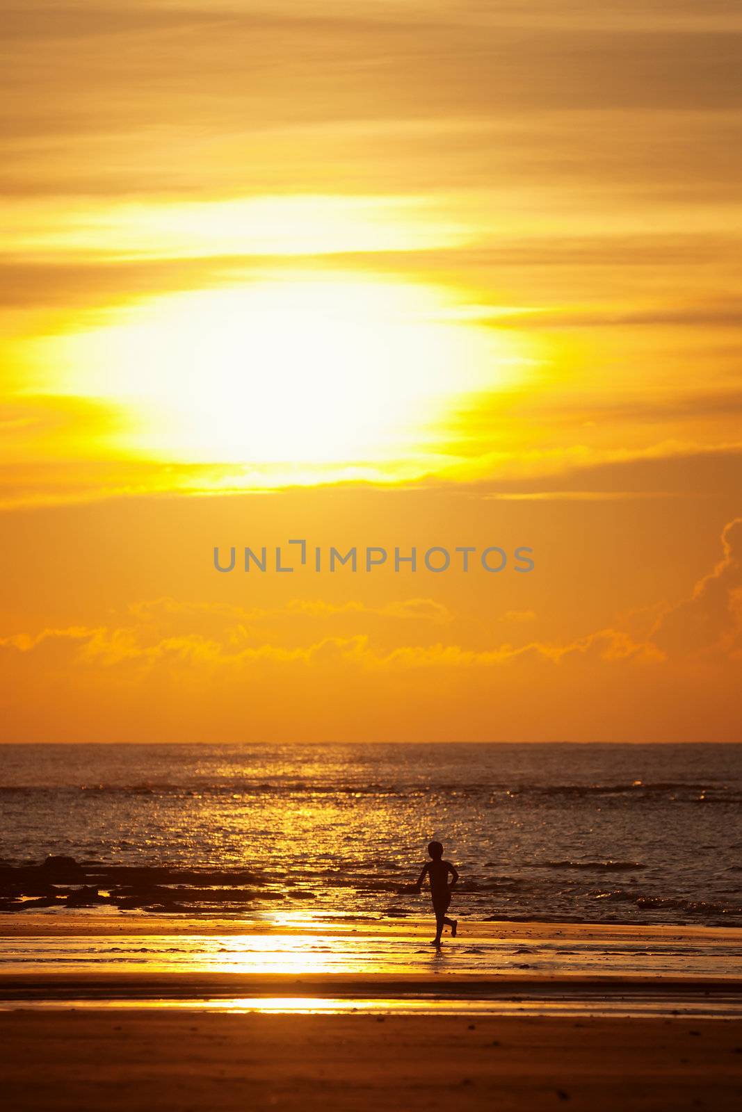 Sunset on a tropical beach and silhouette of a kid
