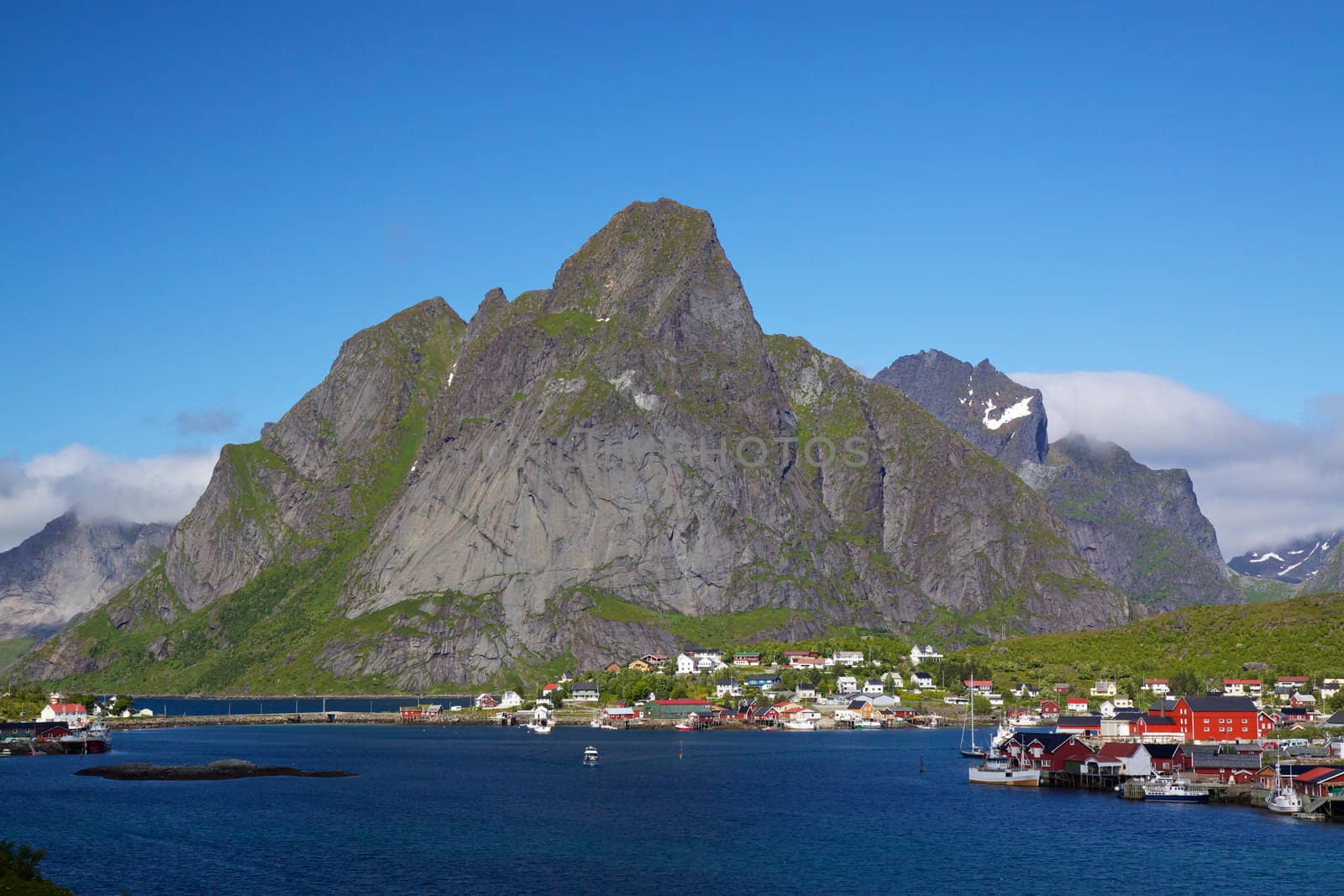 Picturesque town of Reine by the fjord on Lofoten islands in Norway with high mountain peaks towering above