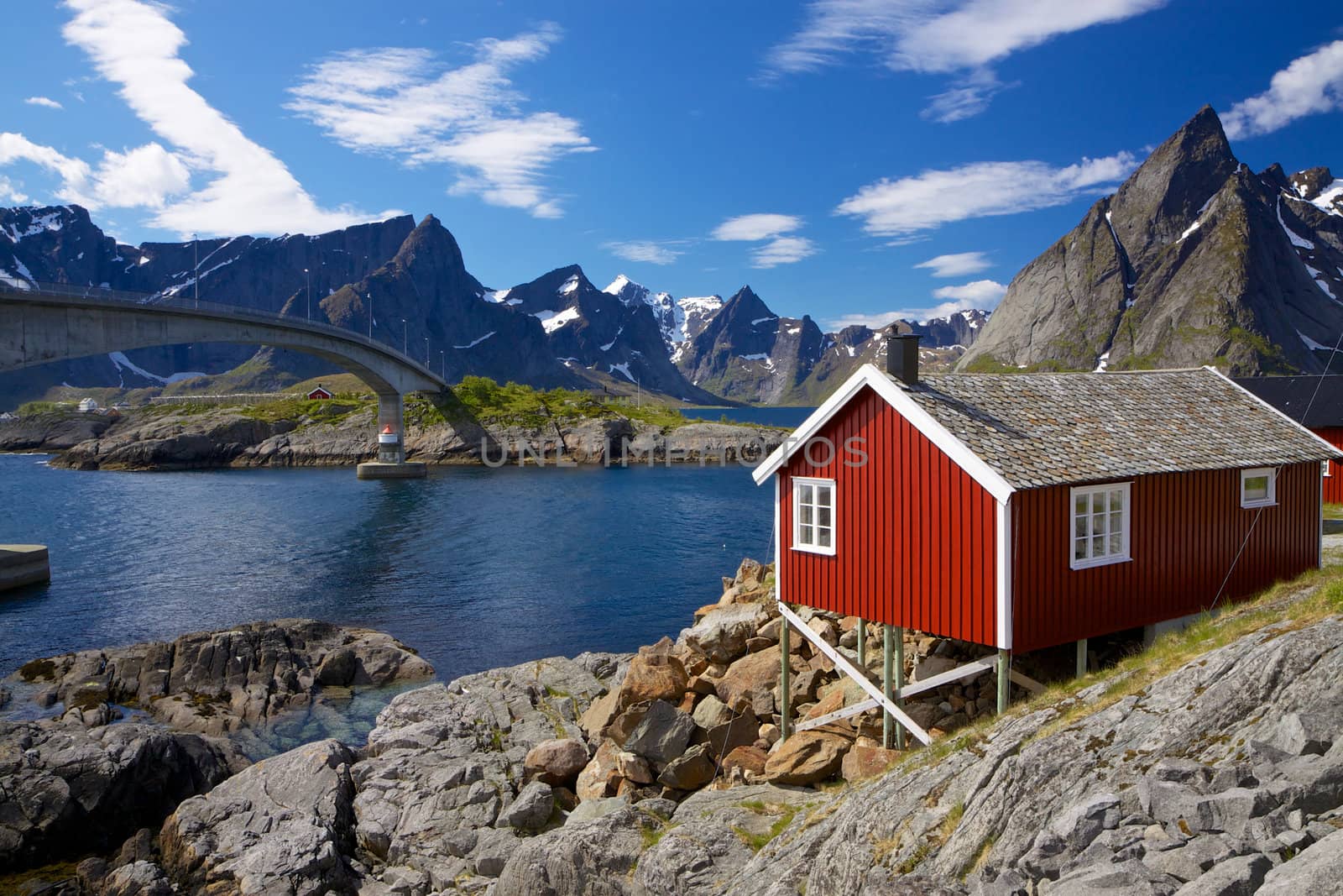 Traditional red fishing rorbu hut on Lofoten islands in Norway near bridge connecting islands