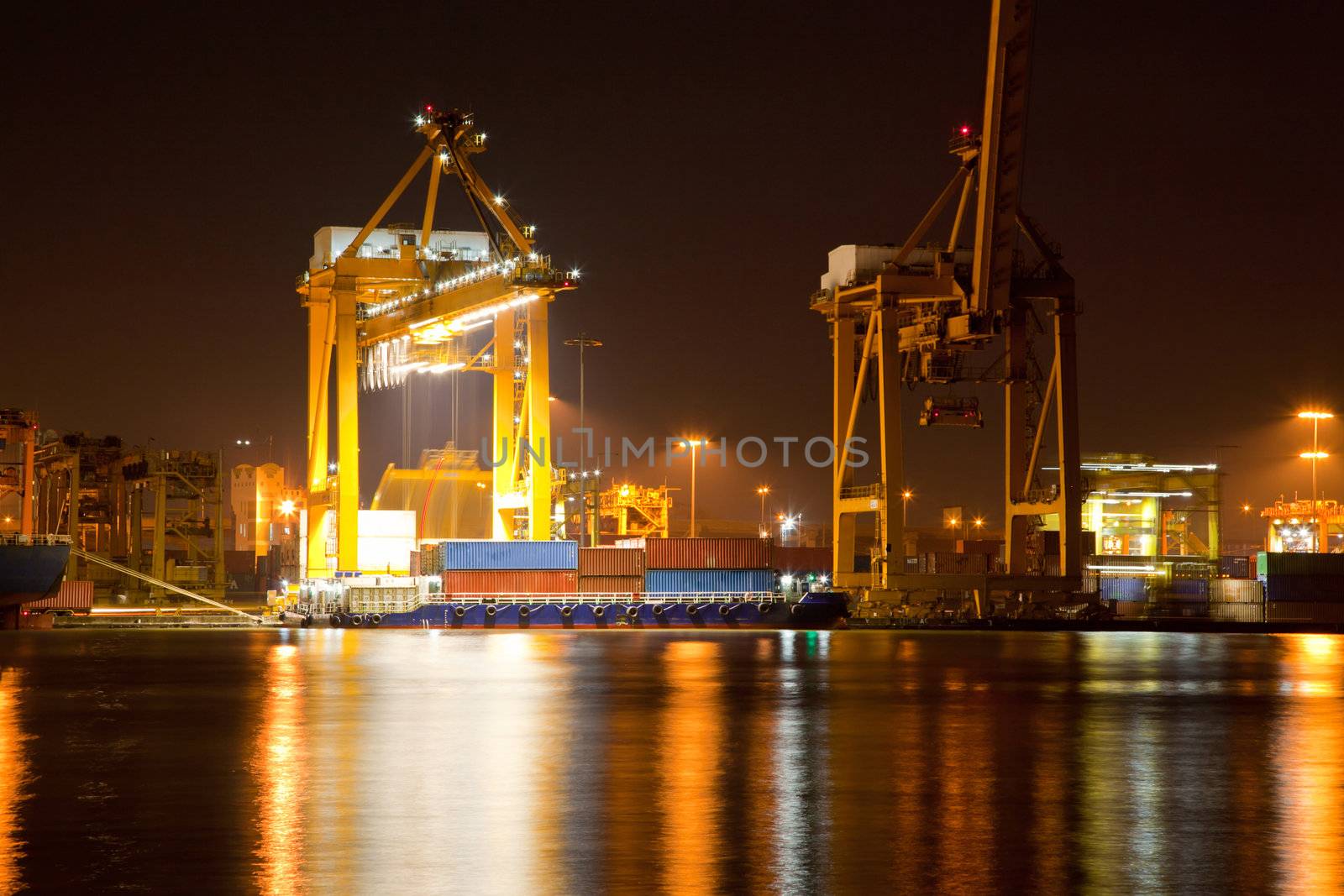 Container Cargo ship with working crane in shipyard at dusk unloading goods for Logistic Import Export background