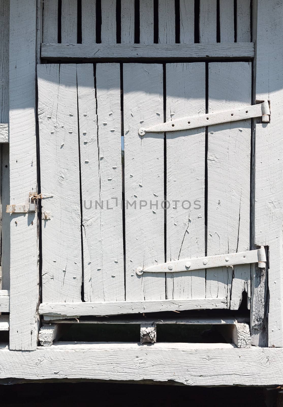 Antique wooden barn door painted white and worn and rotted