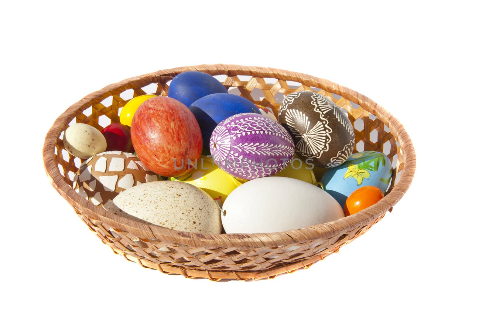 Painted Easter eggs in wicker dish. Festive table decoration.