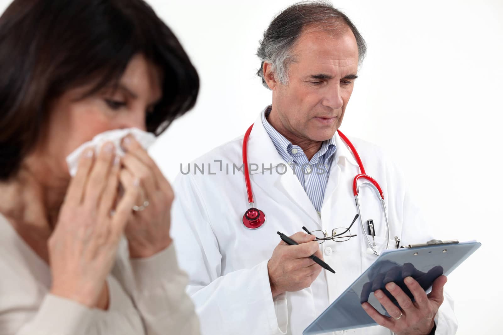 A woman blowing her nose at the doctor.