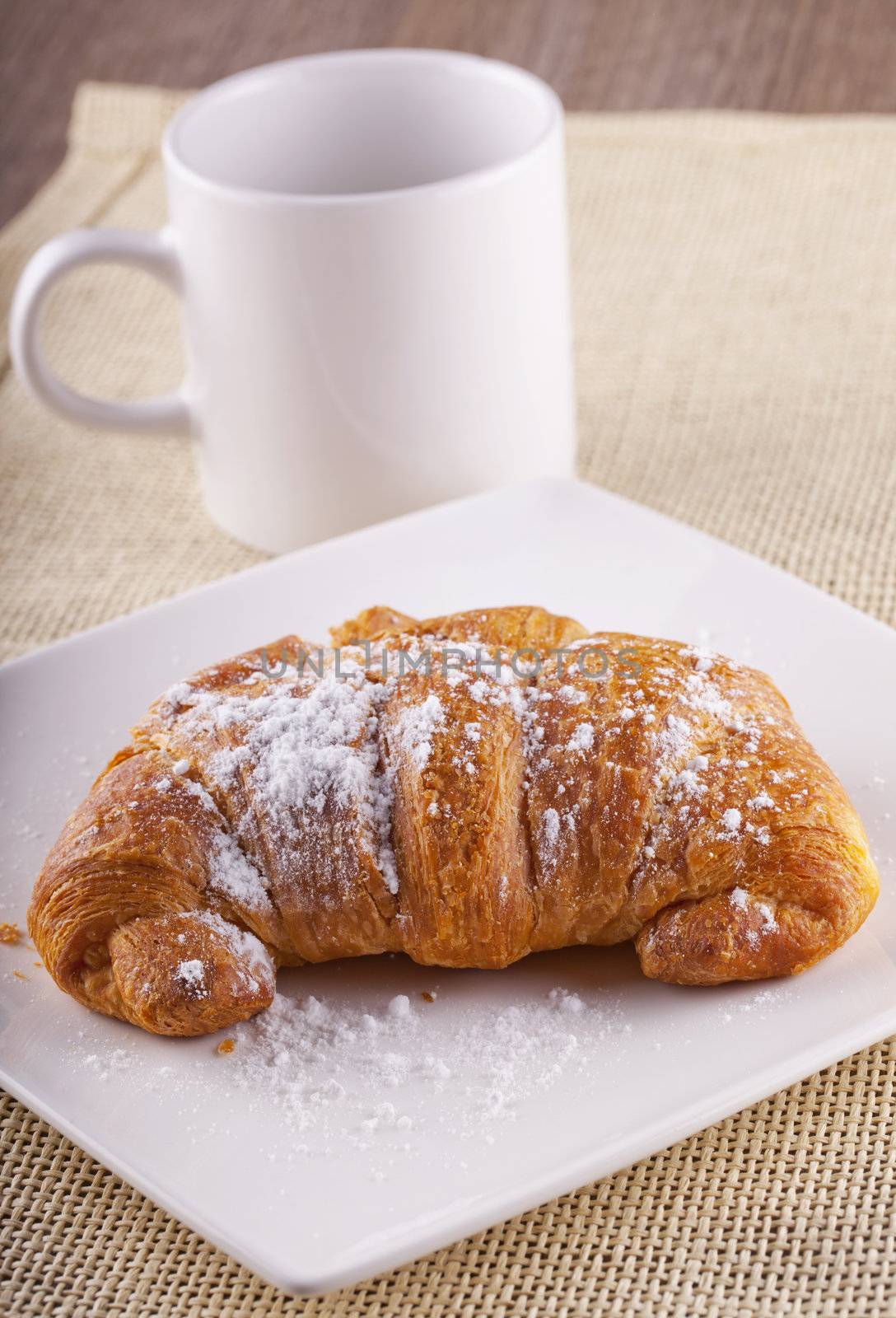 Full view of croissant with white cup on the back