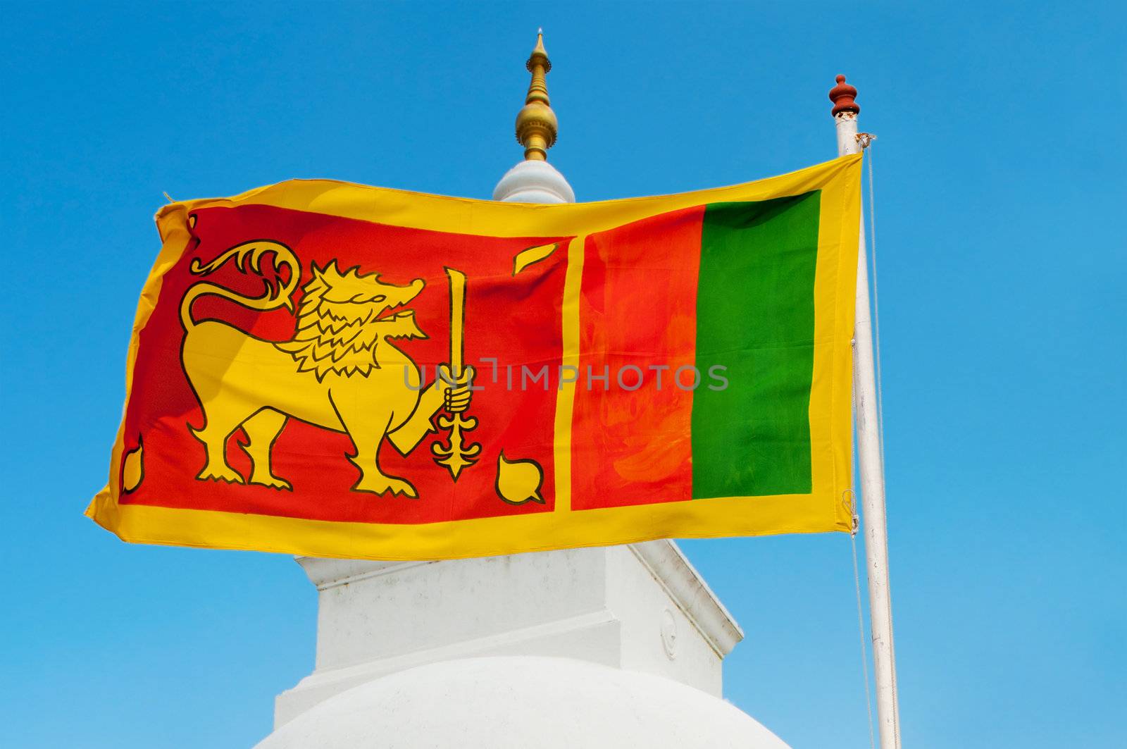 Sri Lanka flag on flagstaff with blue sky and traditional stupa on background.