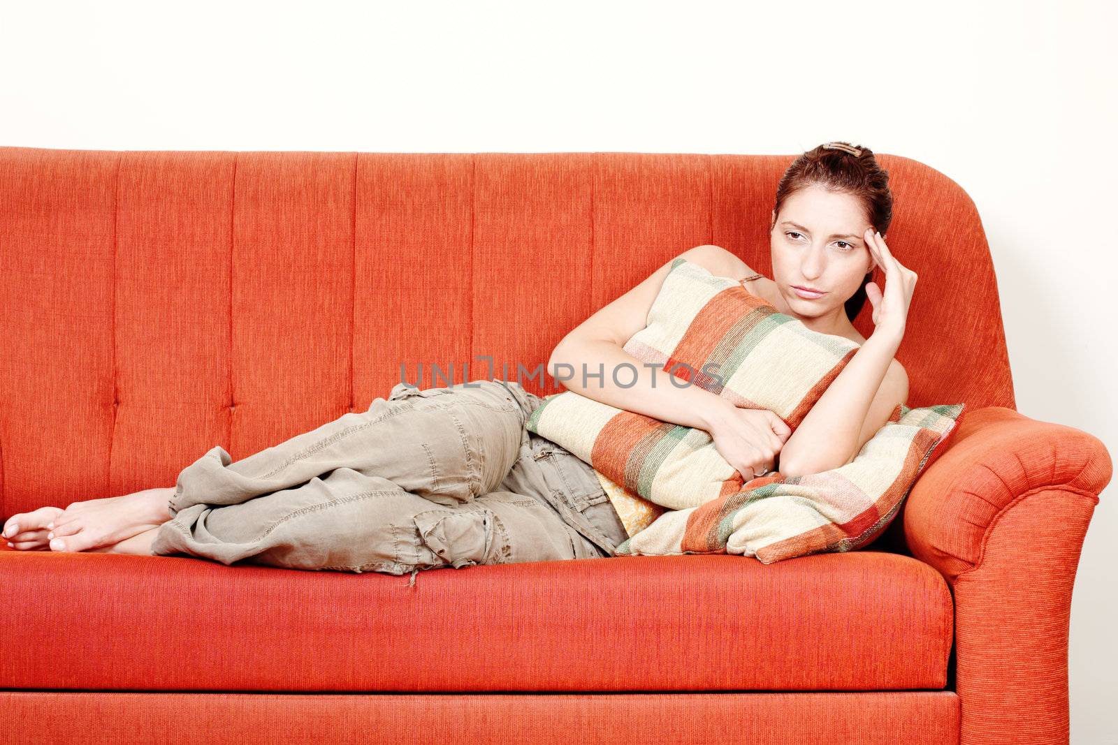 Woman with headache laying on sofa at home by imarin