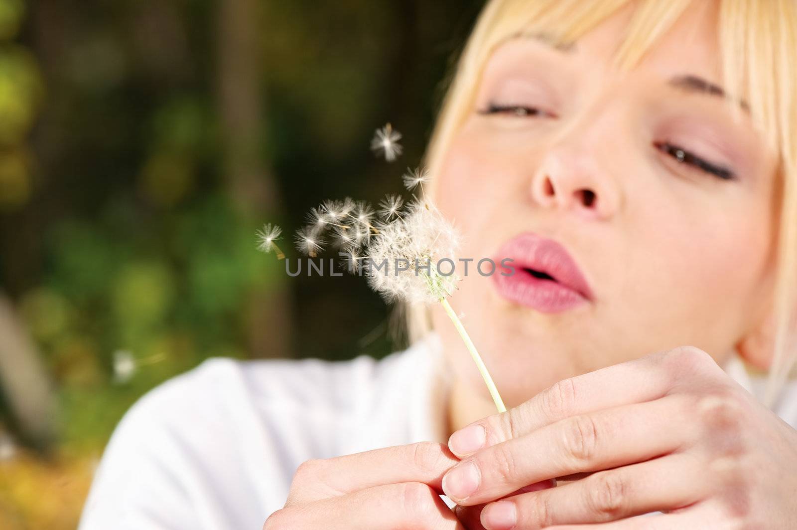 Blond woman blowing spring flower, motion blur