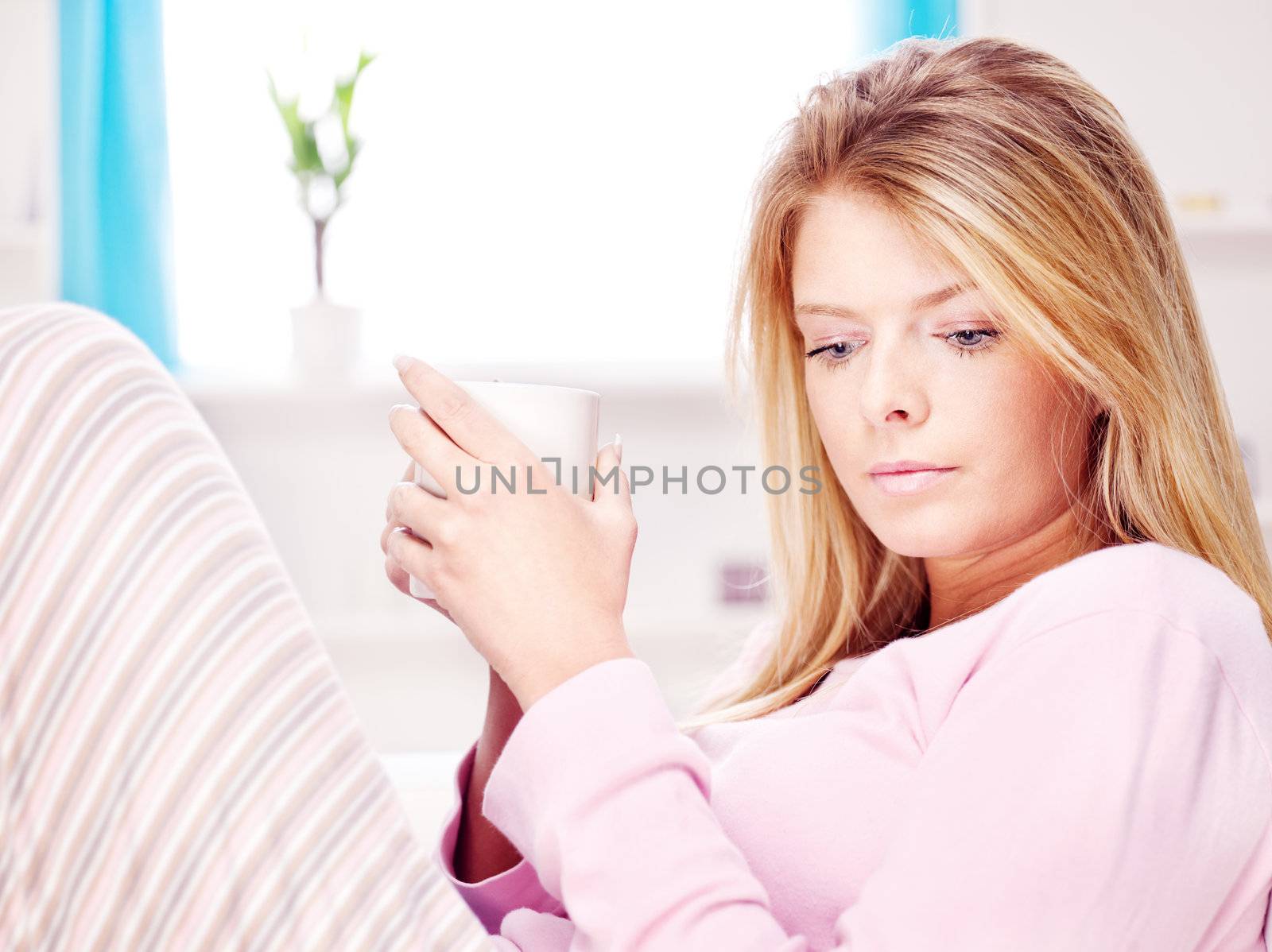 Conceived blond woman at home holding cup of tea