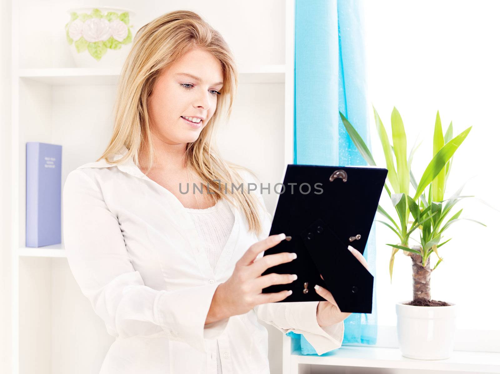 Happy woman holding frame of photo at home