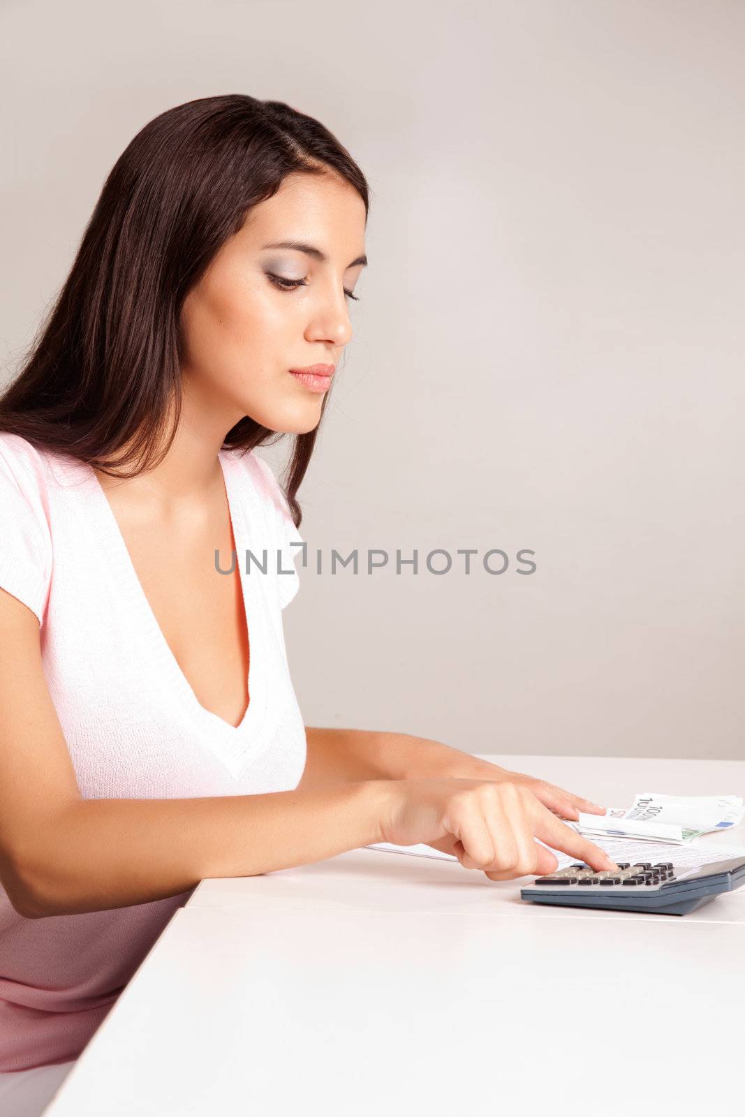 A content women calculating her finances at a desk with money and a calculator