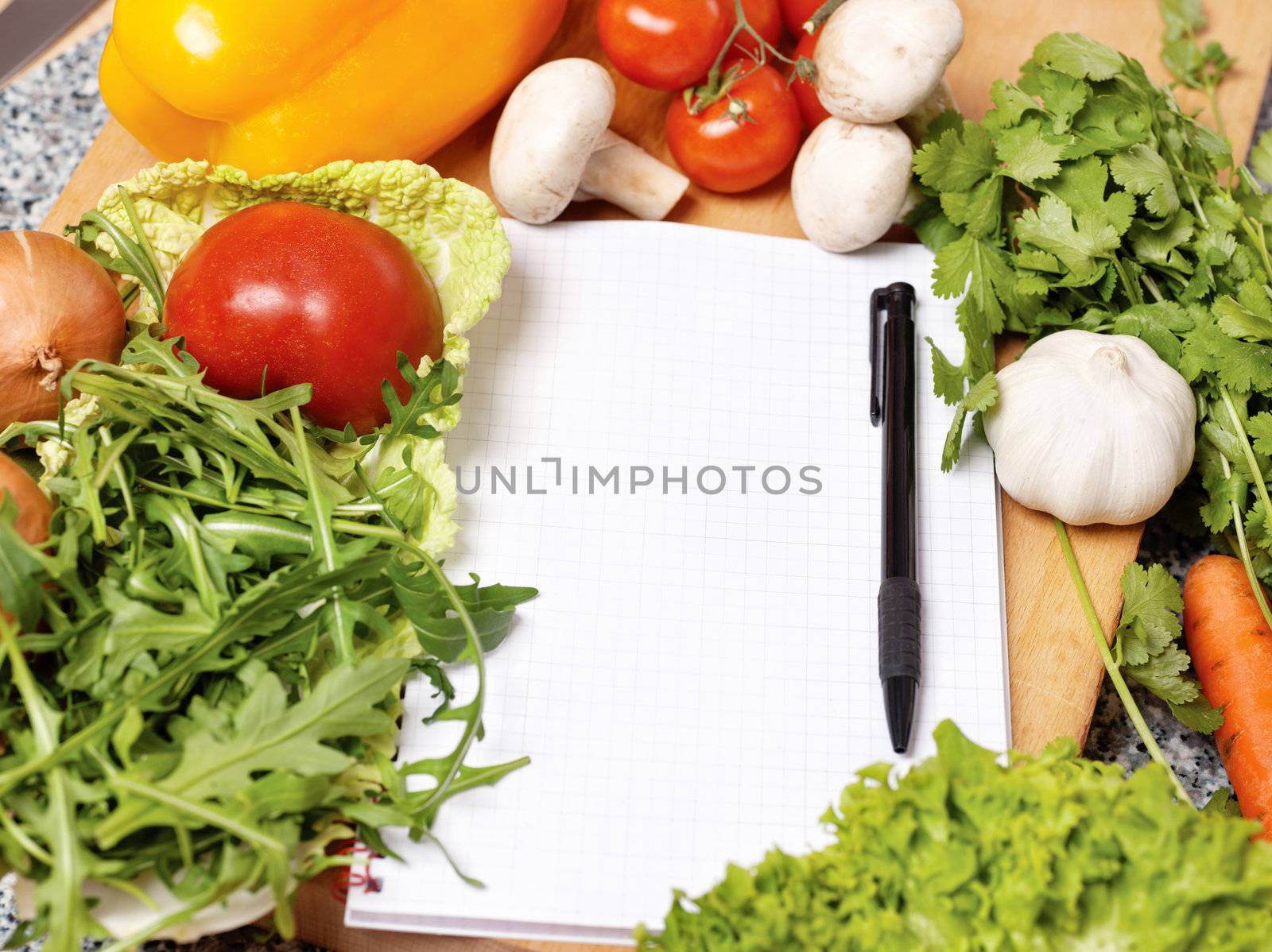 Note book among the vegetables for writing recipe