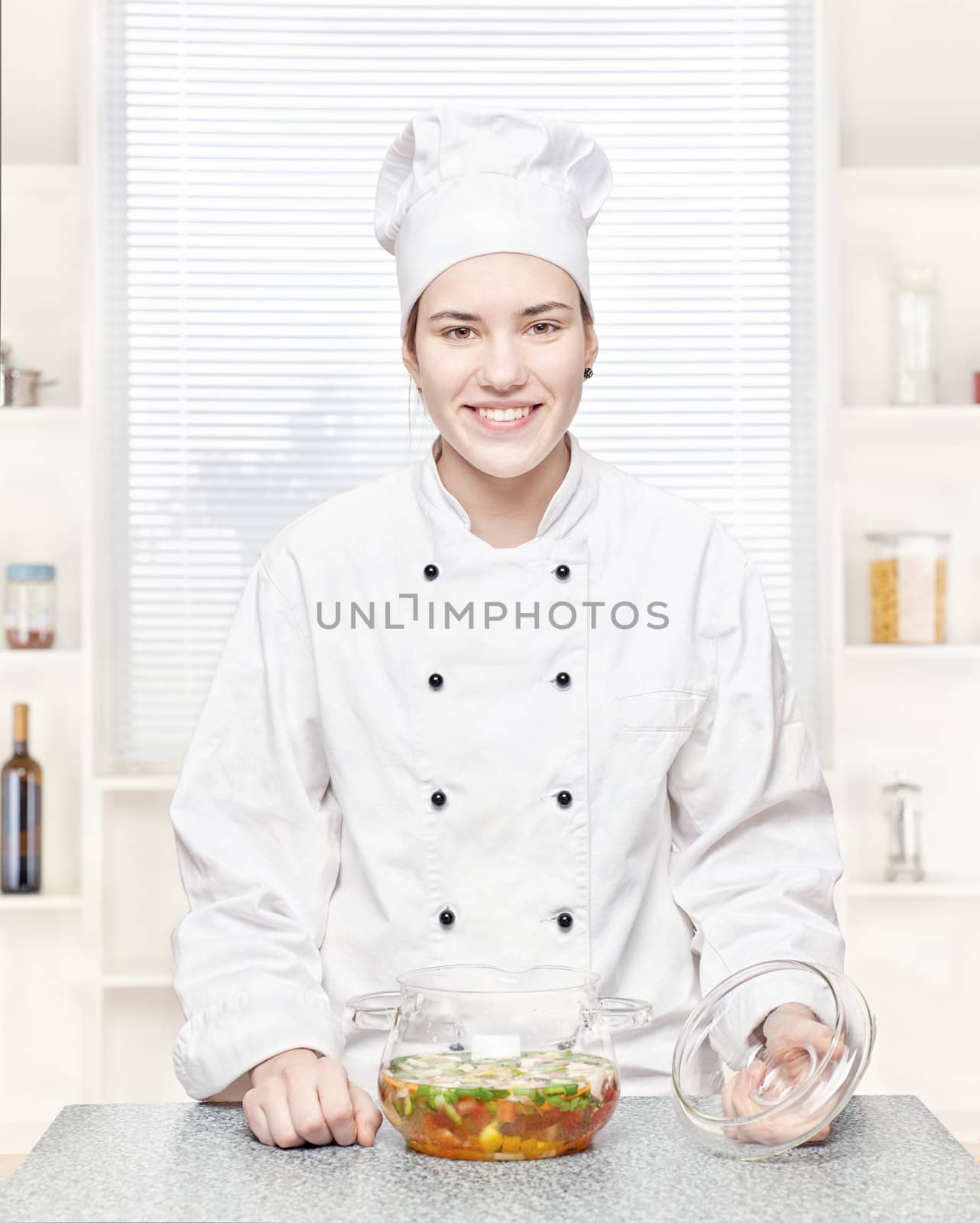 Chef in the kitchen with a soup of vegetables in a glass pot