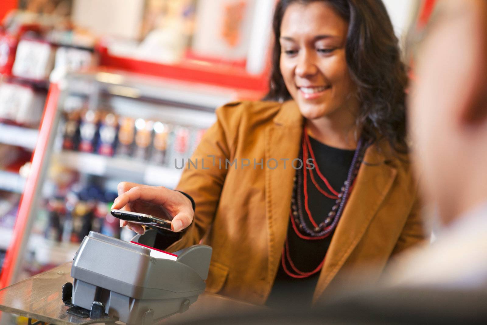 Young woman paying for purchase with cell phone