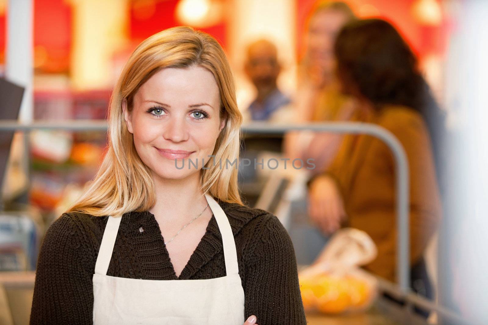 Closeup of a young shop assistant with customer in the background