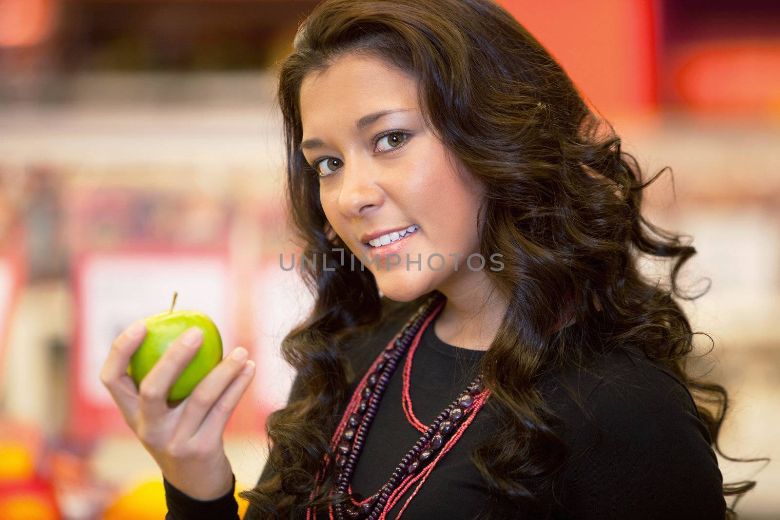 Closeup of a young woman holding apple in the supermarket