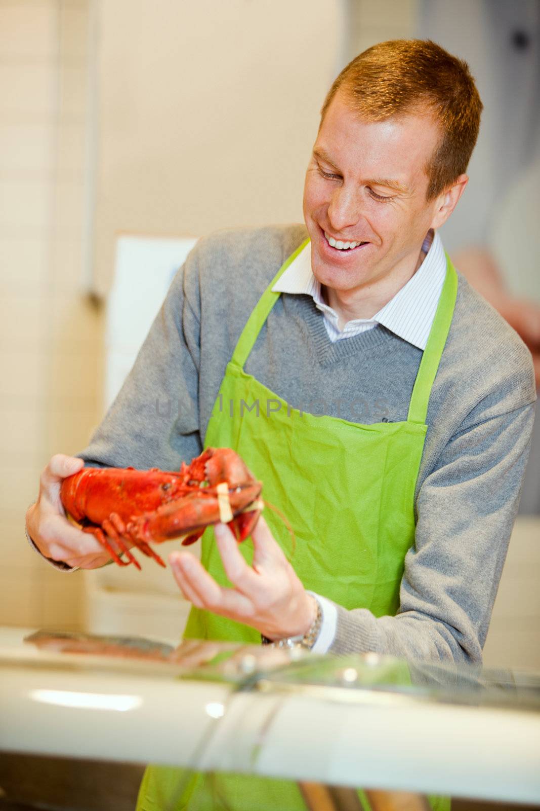 A grocery store worker with a lobster at the fish counter