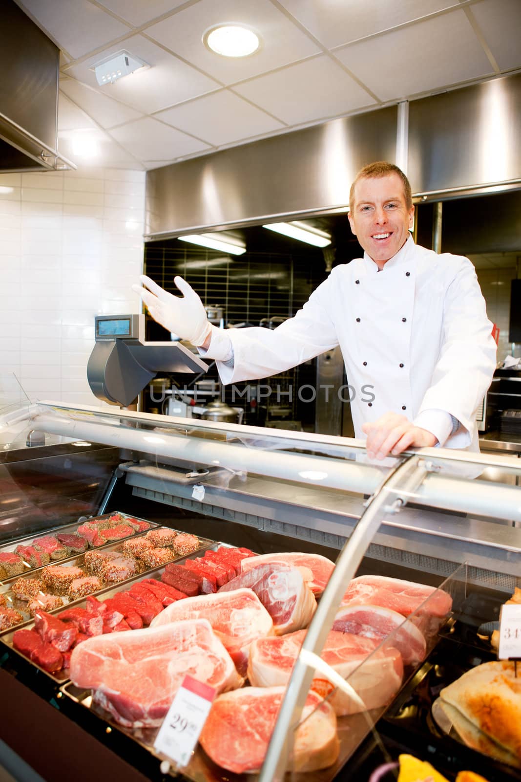 Portrait of a happy butcher welcoming customers to the shop