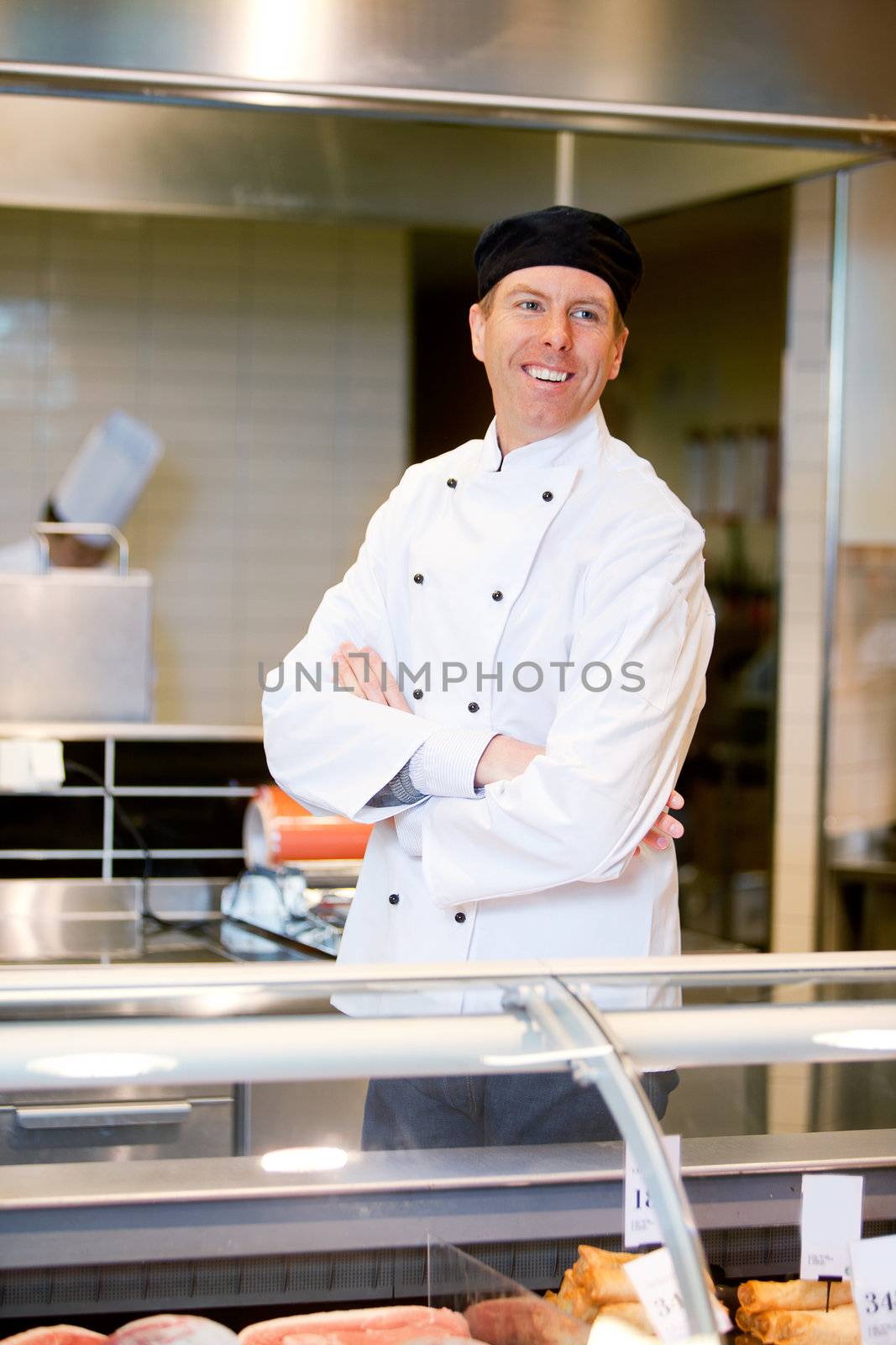 A happy smiling butcher helping a custmer at a fresh meat counter