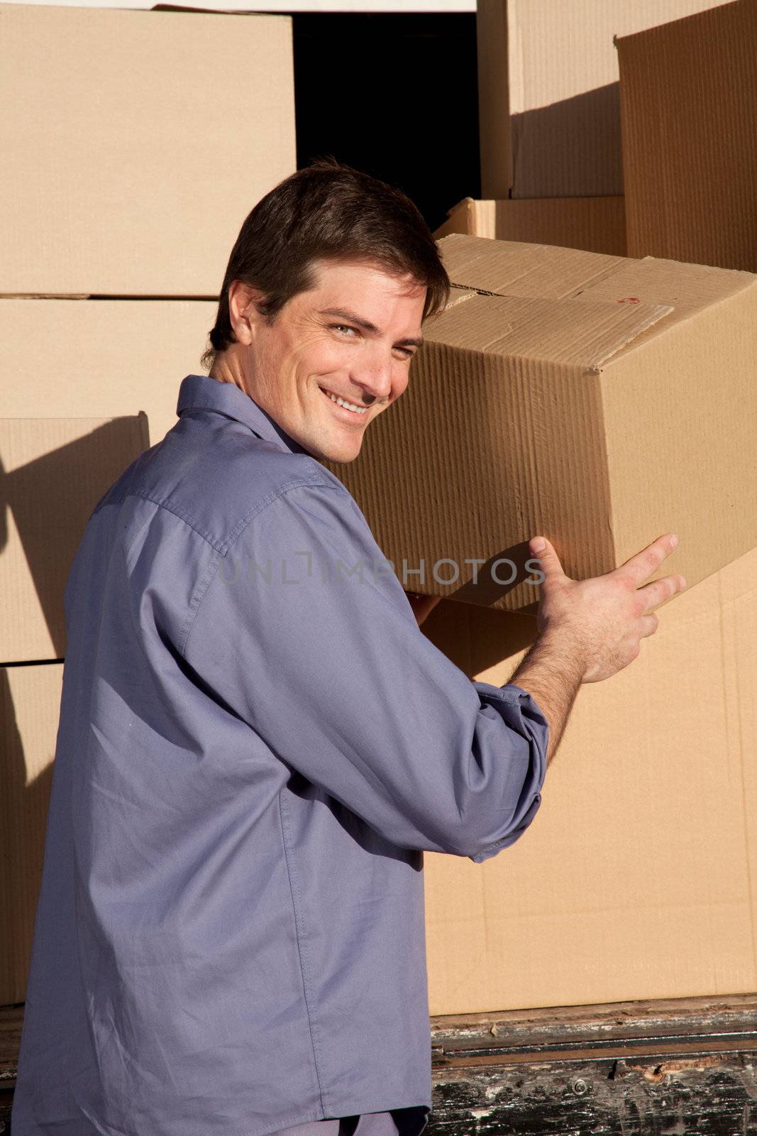 A portrait of a happy mover, moving cardboard boxes
