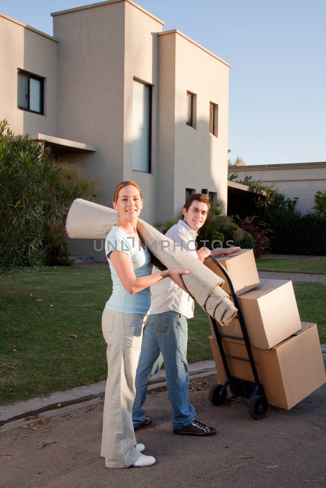 Portrait of a happy couple with moving boxes and small rug