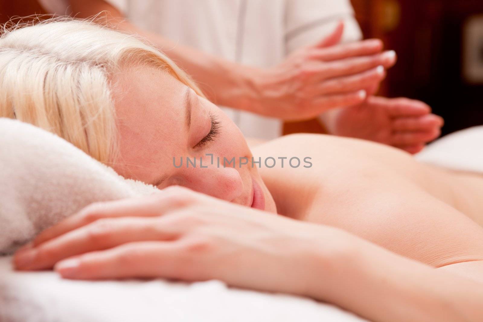 A relaxed blond woman receiving a percussive massage in a spa