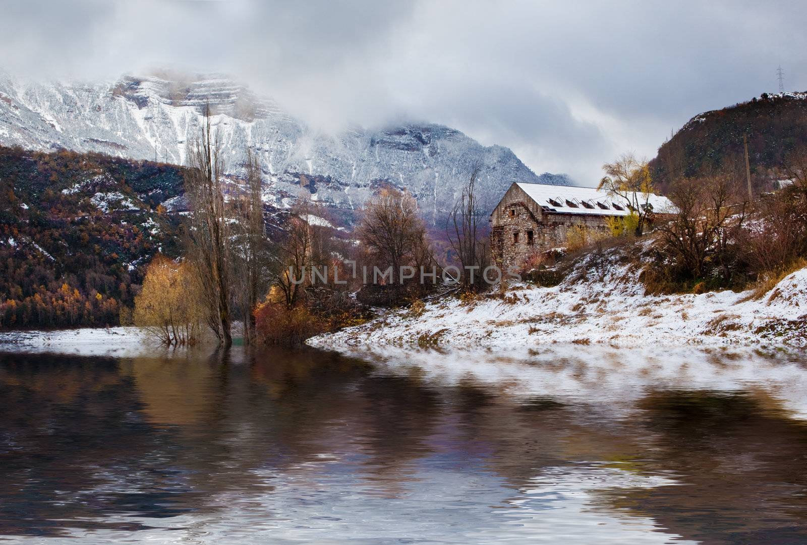 Snowy mountain landscape with house and lake