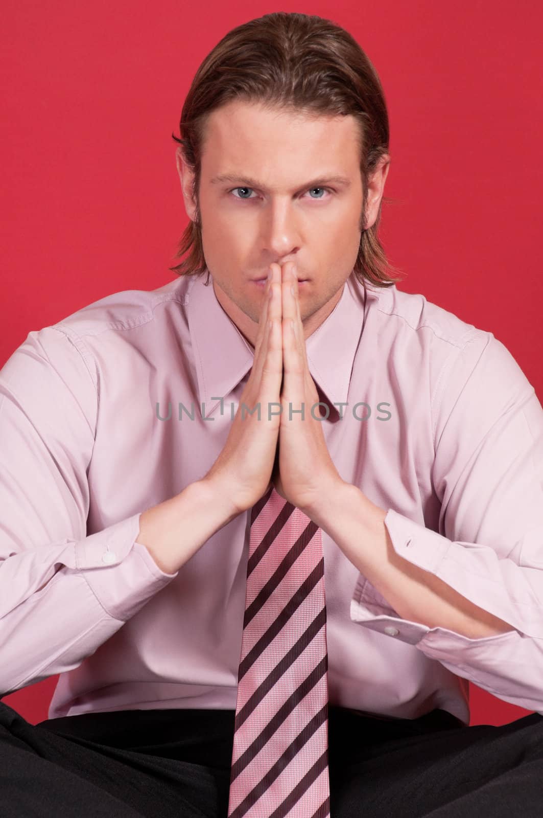 Portrait of a thoughtful businessman with hand clasped against red background