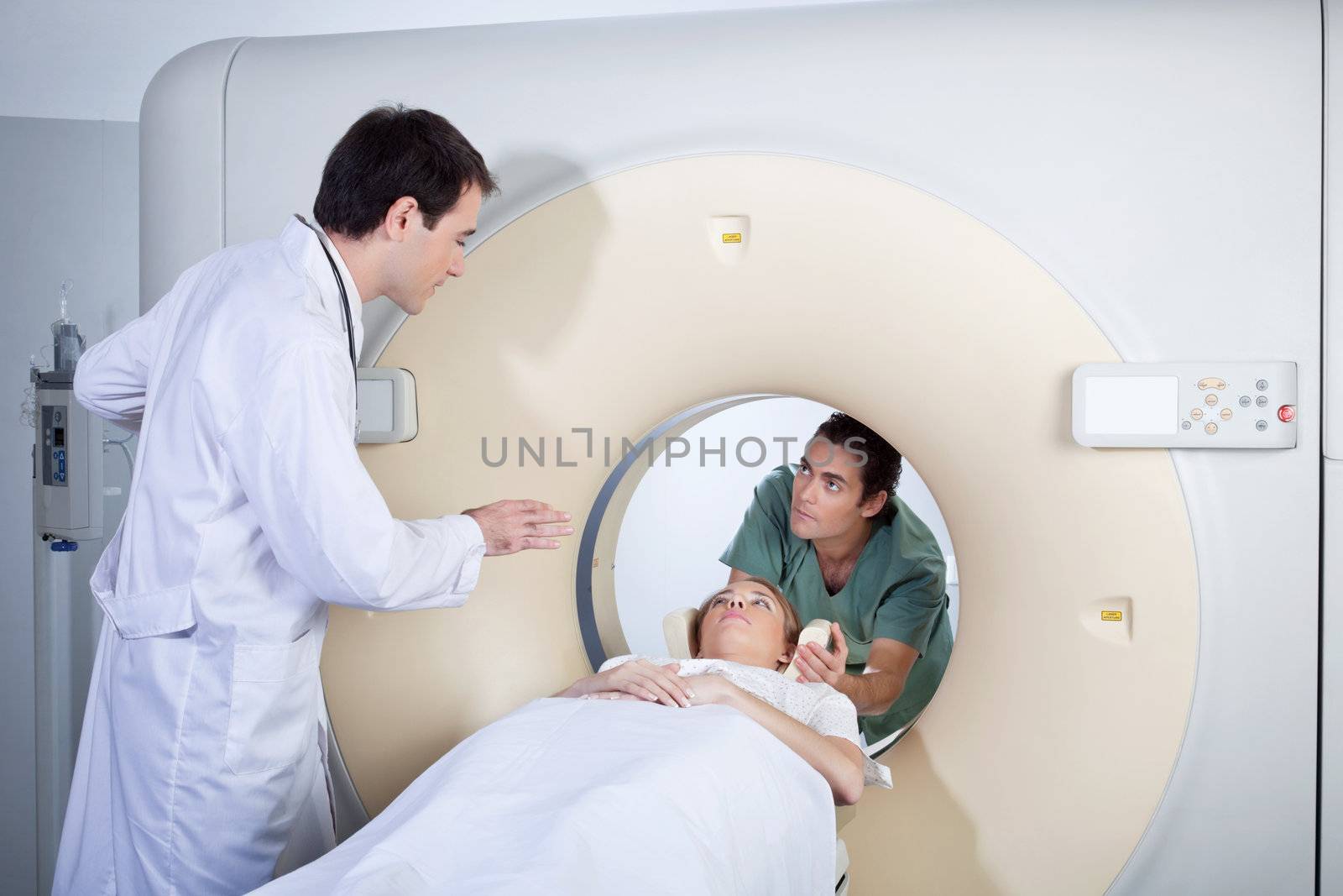 Doctor instructing technician while preparing patient for MRI scan