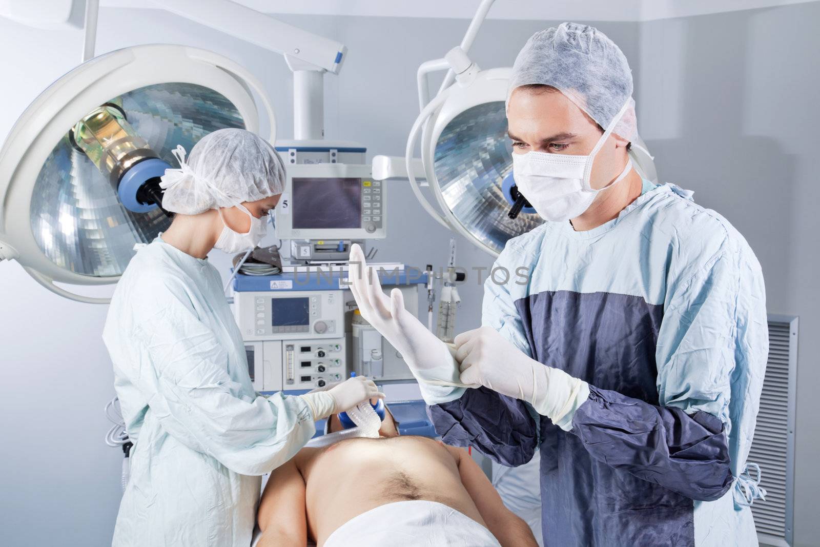 Nurse applying gas mask to the patient while doctor wearing glove