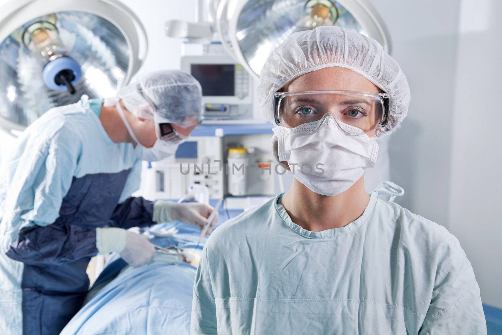 Portrait of female surgeon with doctor doing surgery in background