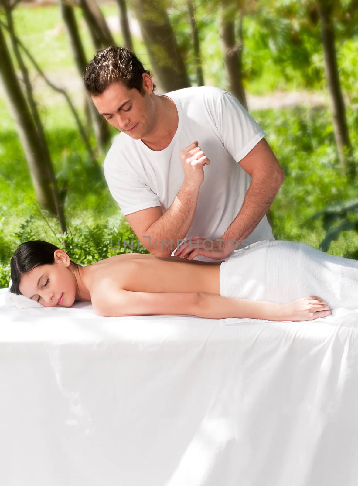 A male masseur giving a massage to a woman outdoors