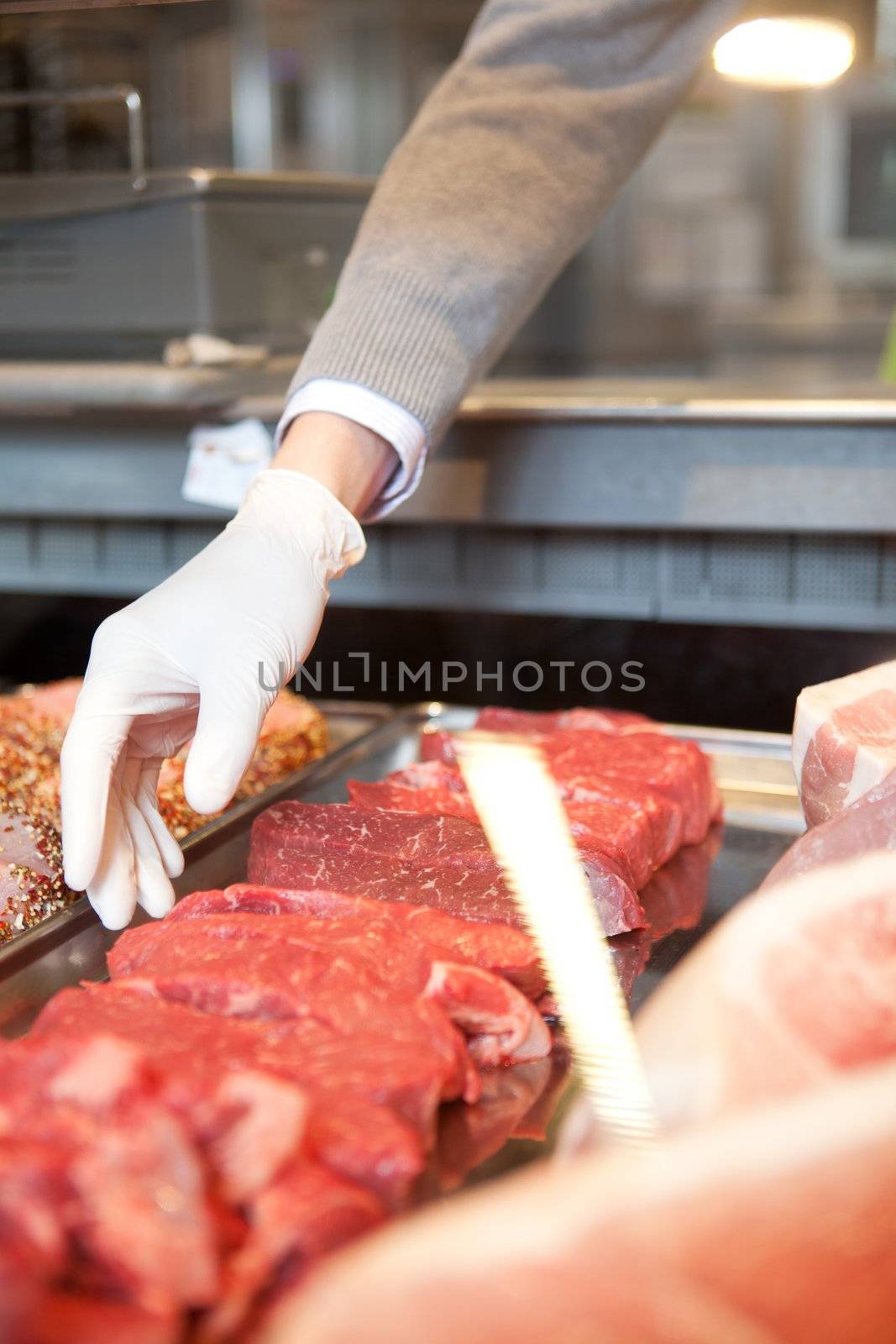 A butcher's hand reaching into a cooler picking a fresh cut of meat