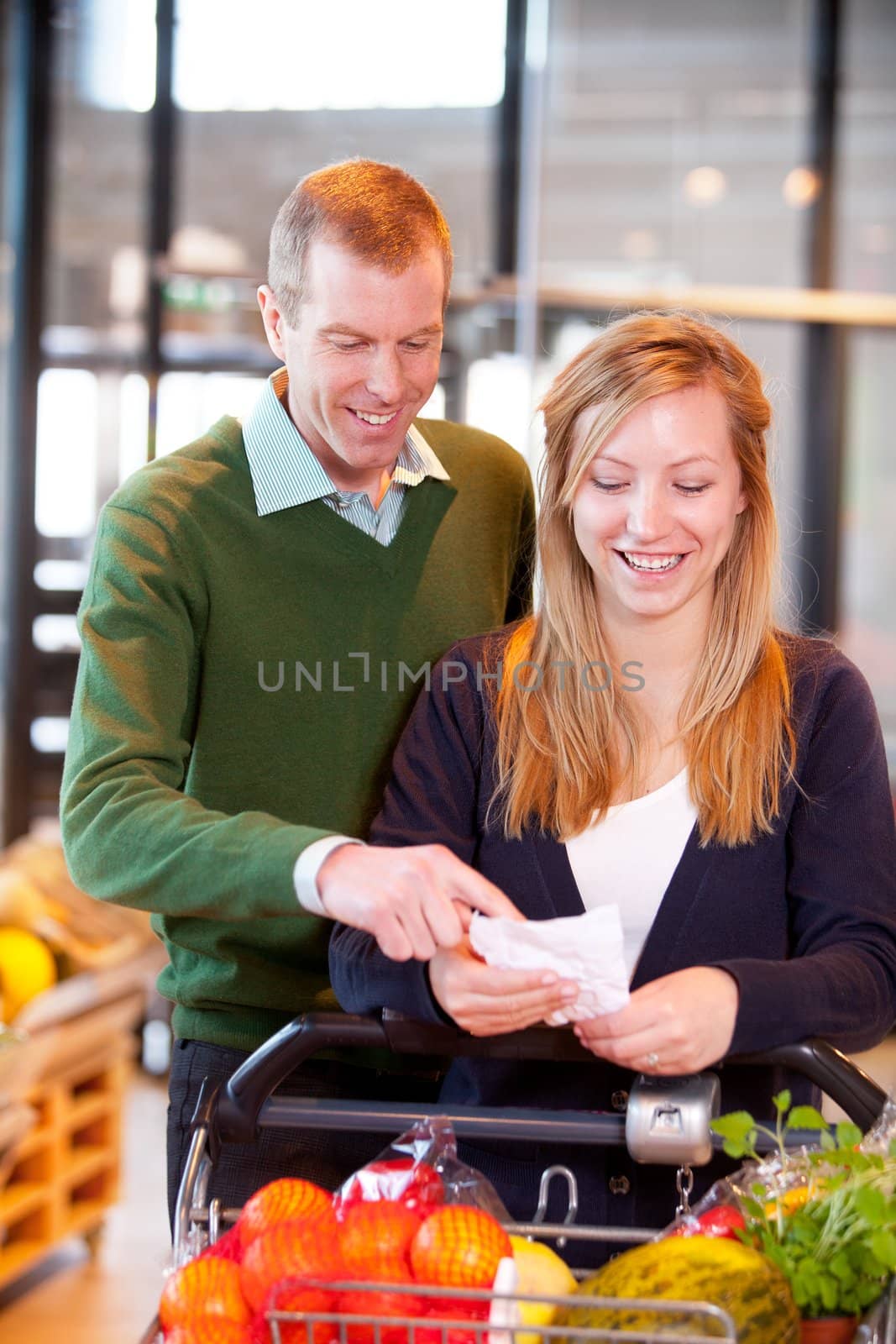 A happy couple looking at a grocery list in a supermarket