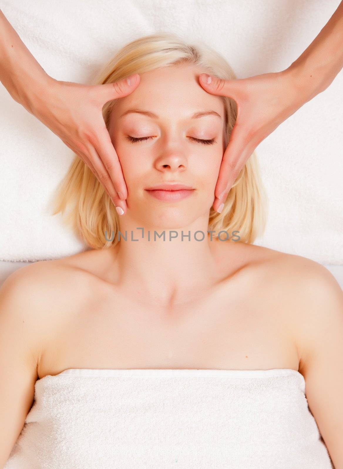 A beautiful blonde woman receiving a stress reducing head massage at a spa