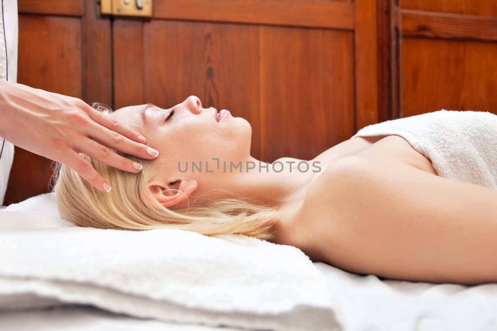 Side view of young blond woman receiving head massage at spa