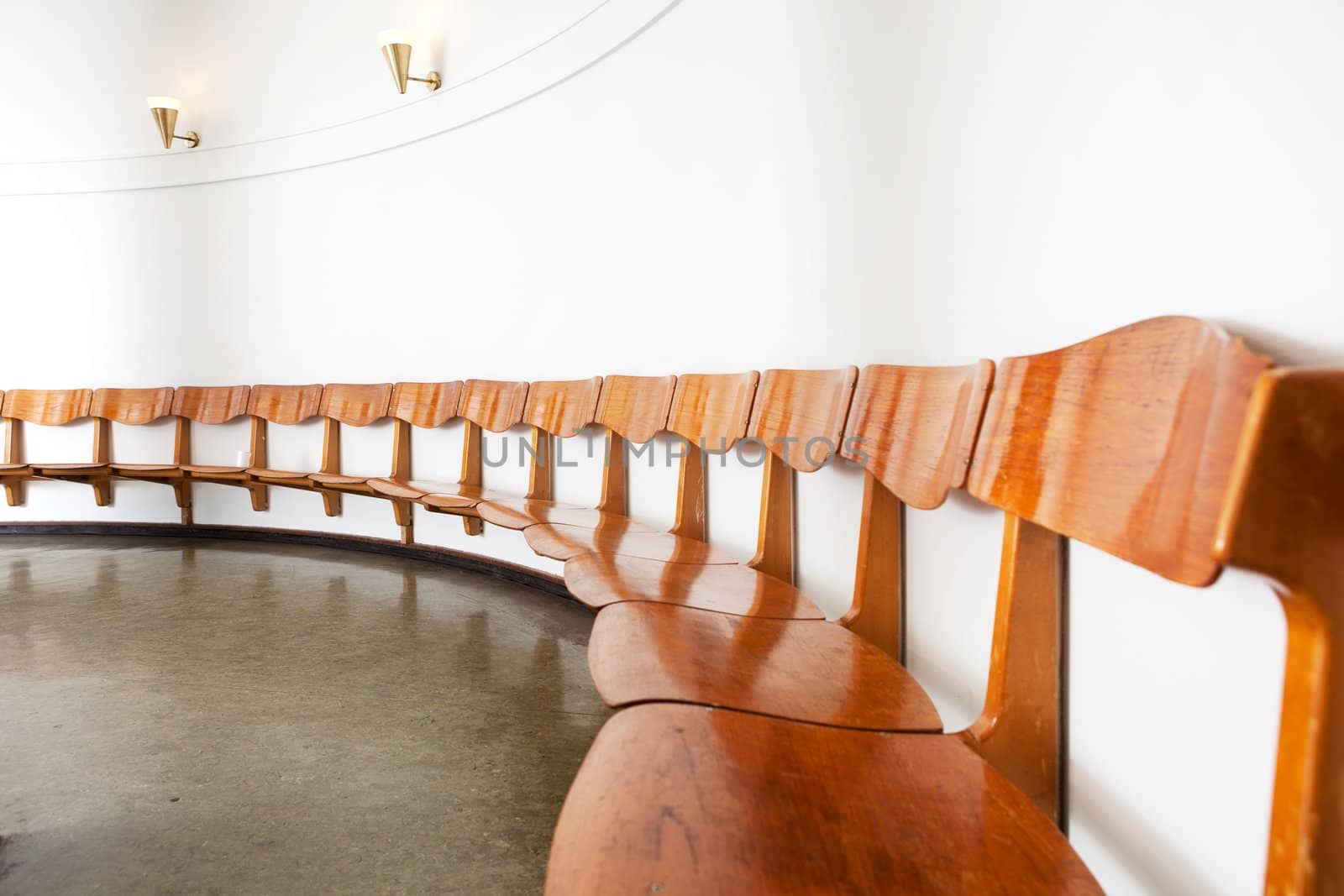 An old, functionalism styled recption interior with wooden seating in a round room