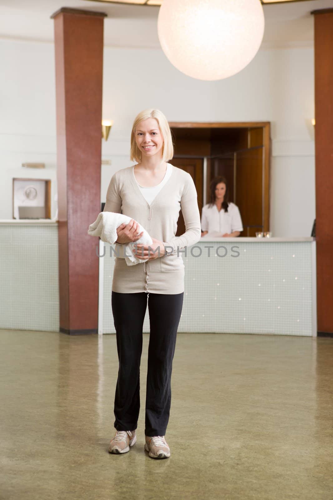 A woman in an old style spa reception with towel in hand.