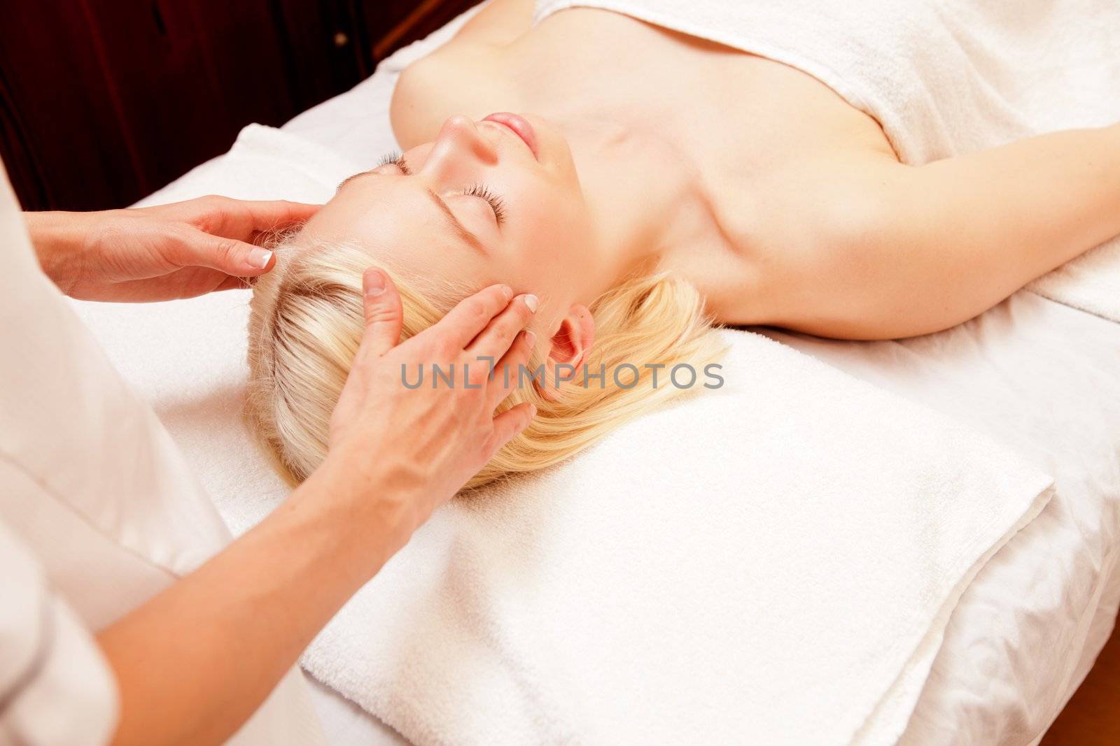 A pretty young woman receiving a scalp massage in a spa