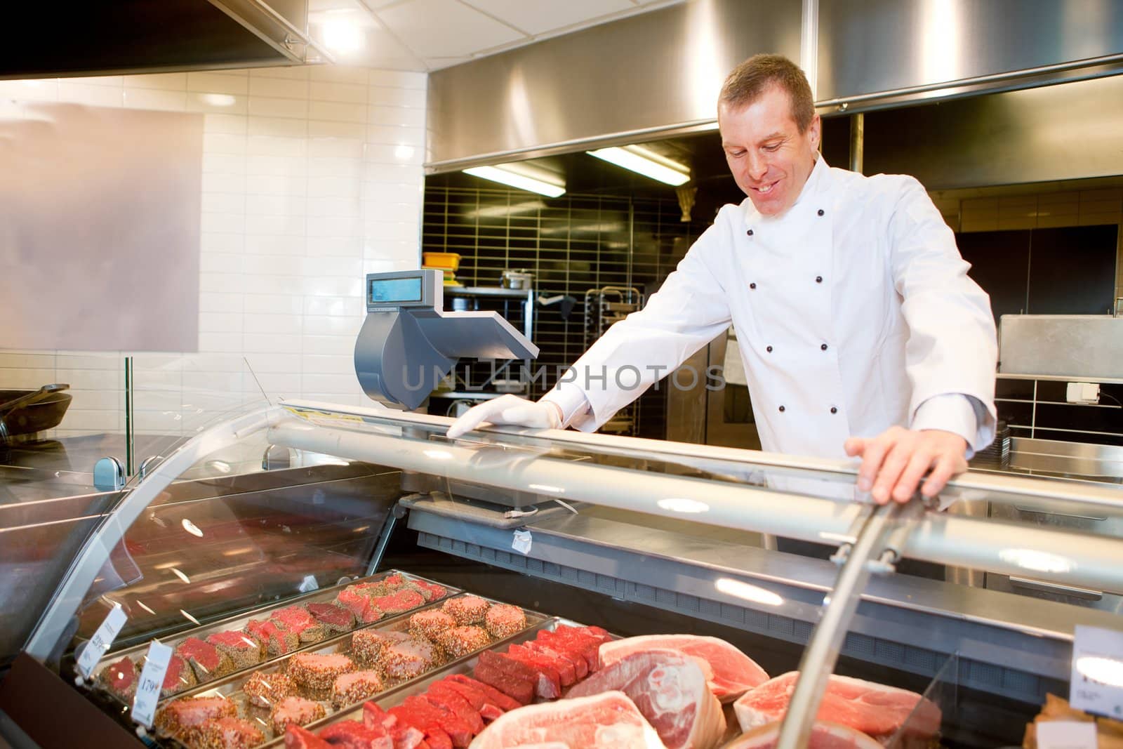 A butcher at a fresh meat counter in a grocery store