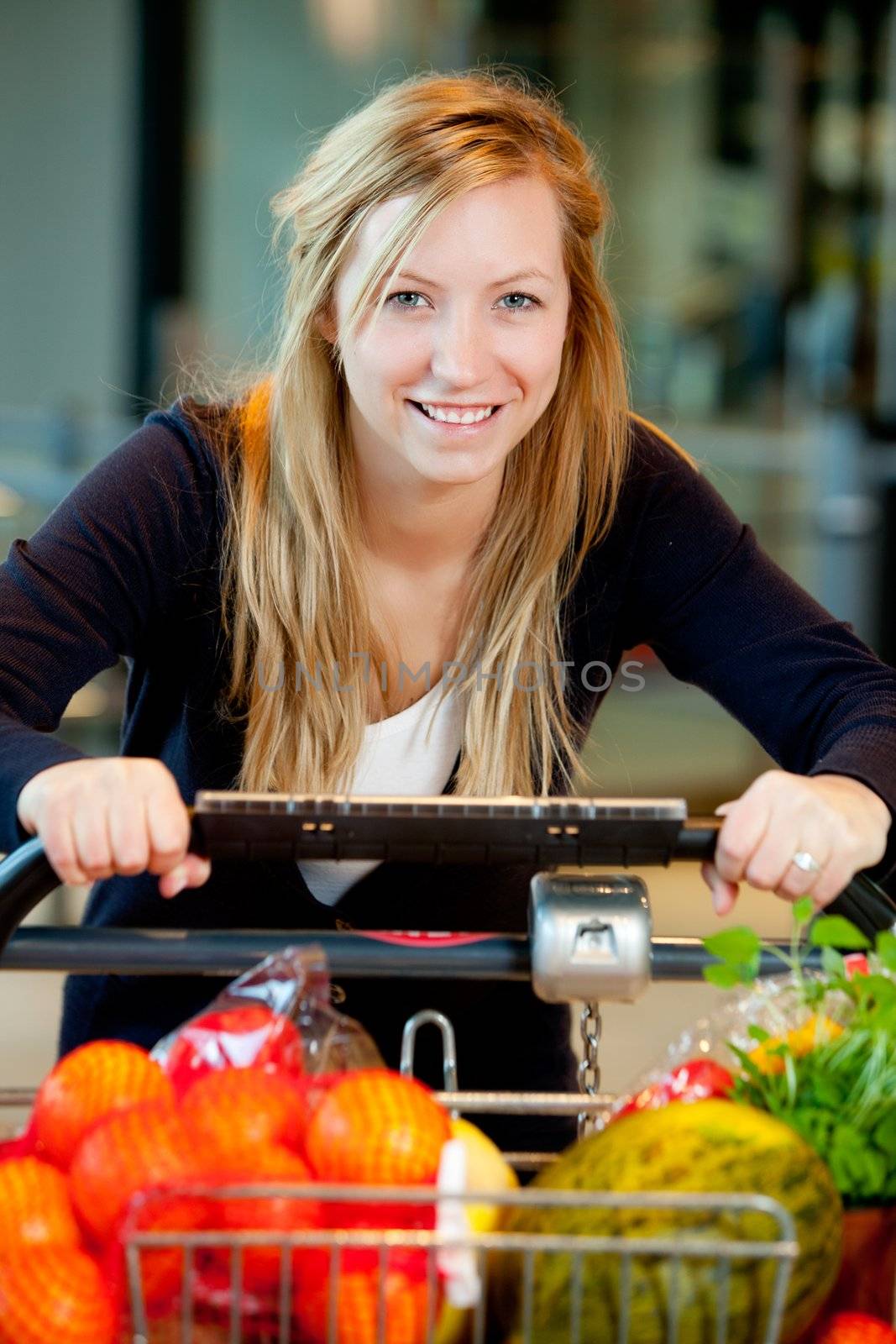 A happy shopping woman with grocery cart full of fruits and vegetables