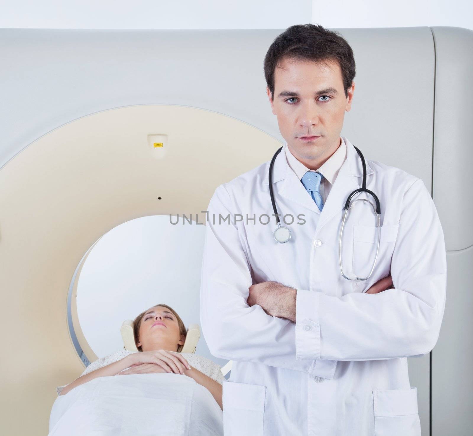 Serious doctor looking at camera in front of ct scanner