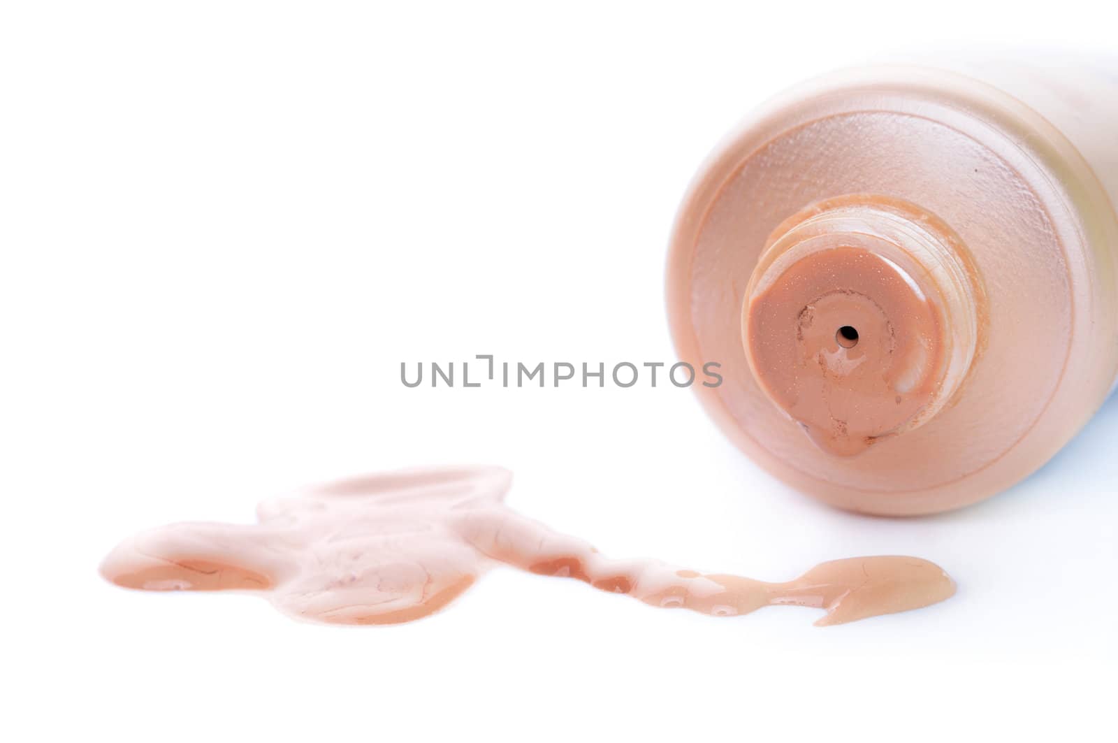 Close-up of open toner cream tube and poured beige cream. Shallow depth of fields. Focus on tube front. Enought space for text.