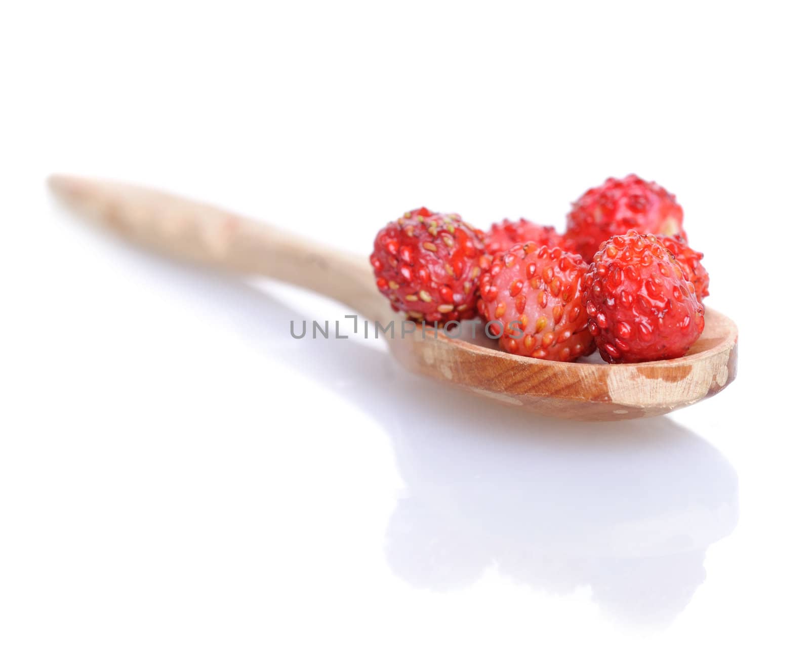 Strawberries in small wooden spoon with soft shadow on white background. Shallow depth of field.