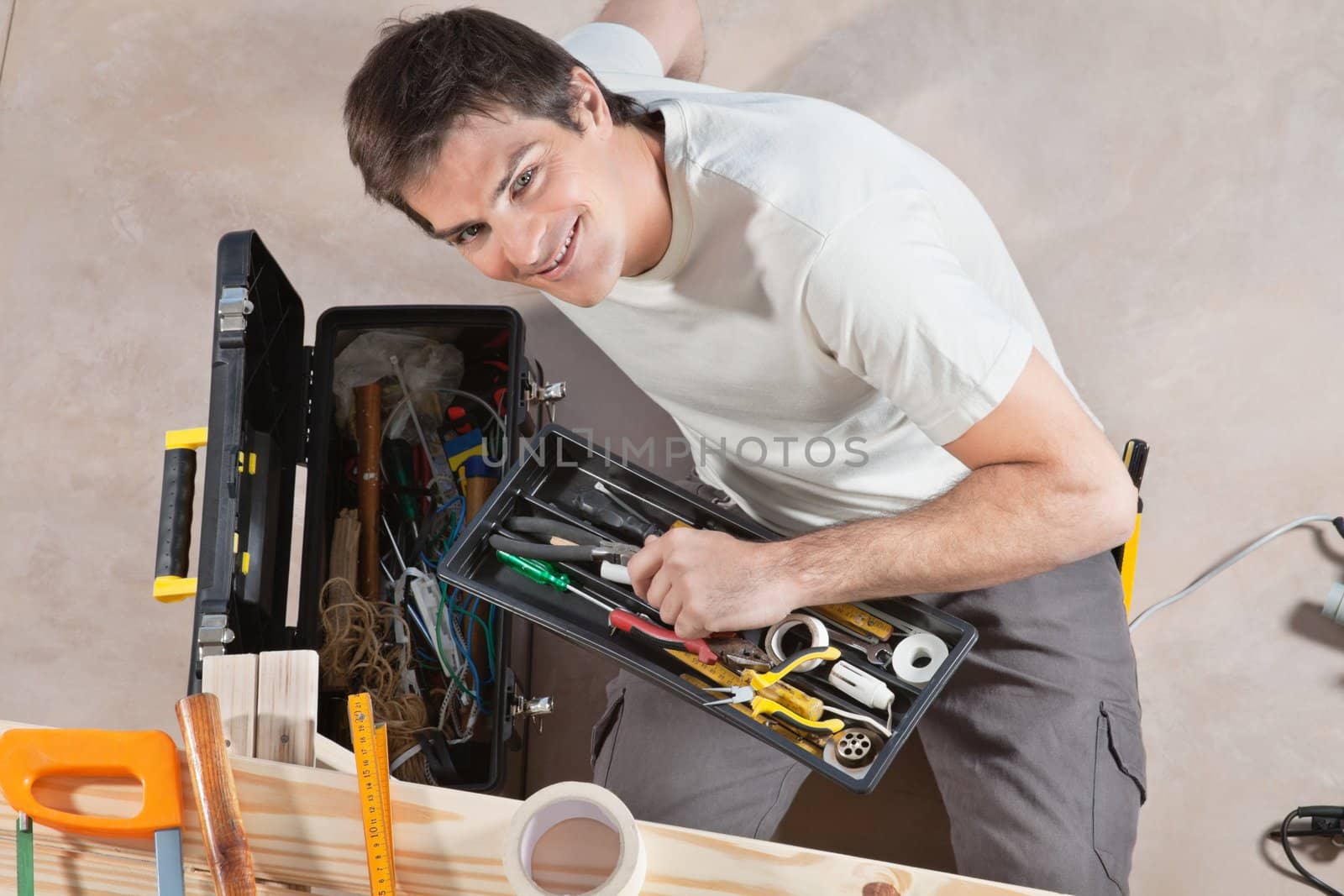 Portrait of smiling young man holding his tool box