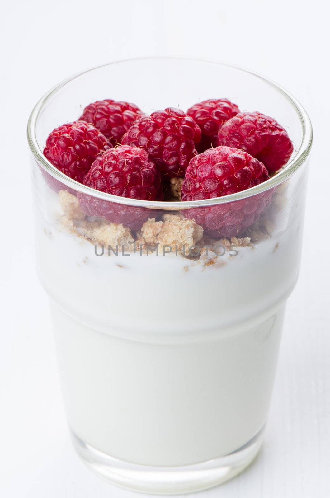 Yogurt with raspberries in  glass on white