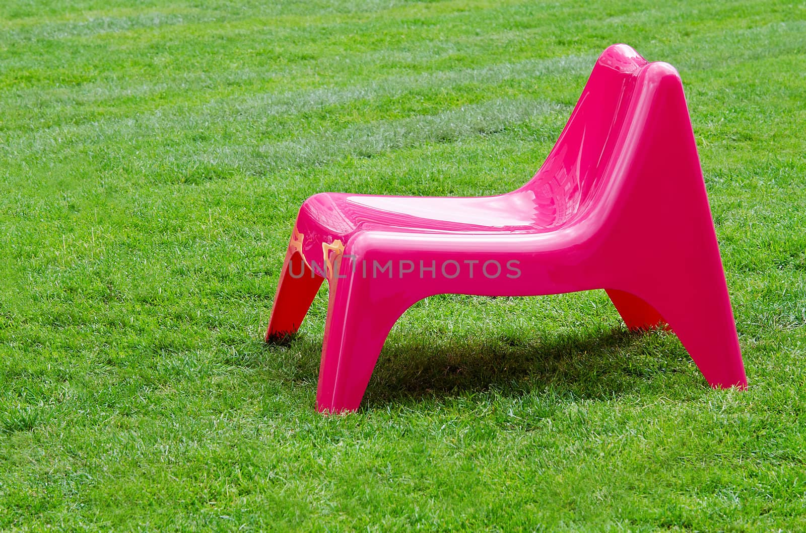 Pink chair on green grass background
