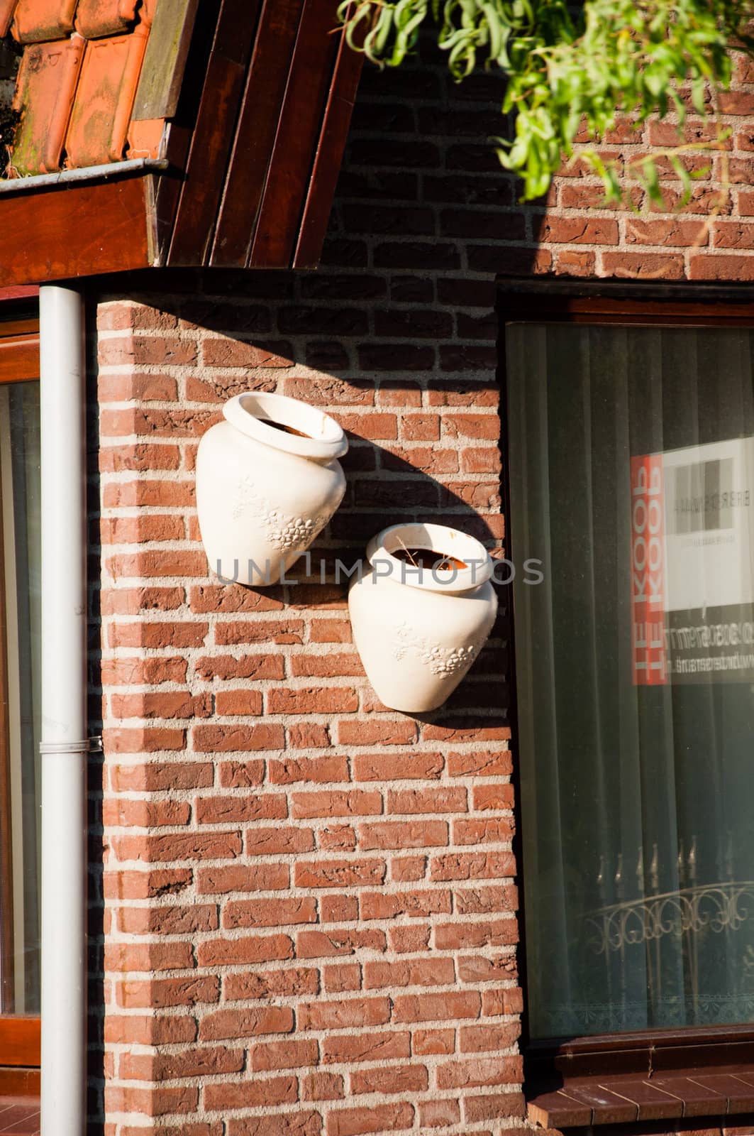 Two clay jars on bricks wall by Nanisimova