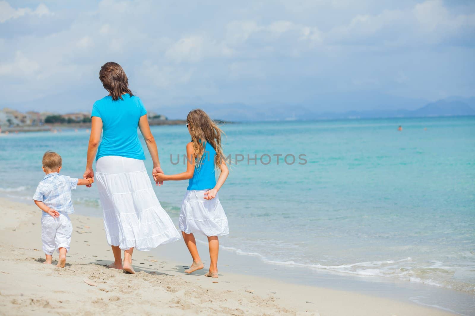 Back view of mother and two kids having fun on tropical beach